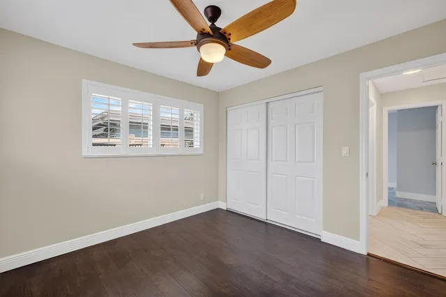a view of an empty room with window and wooden floor