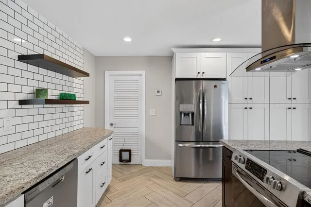 a kitchen with stainless steel appliances granite countertop a refrigerator and a stove