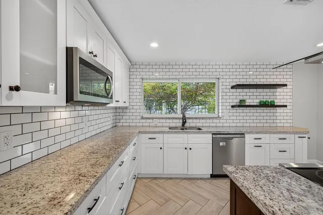 a kitchen with stainless steel appliances granite countertop a sink stove and cabinets