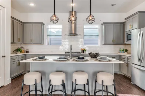 a kitchen with stainless steel appliances granite countertop a sink a stove a refrigerator and island with wooden floor