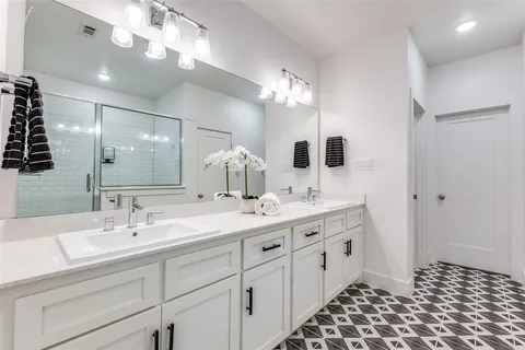 a bathroom with a double vanity sink mirror and shower