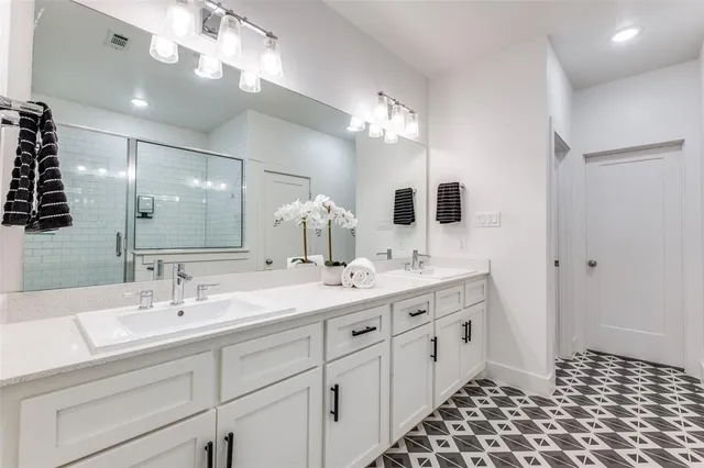 a bathroom with a double vanity sink mirror and shower