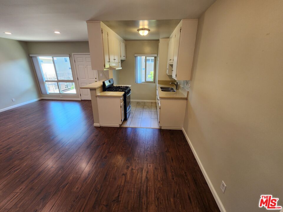 7925 Vineland Avenue, Unit 26 Los Angeles, CA 91352 - Photo 7 of 34 a view of a kitchen and an empty room with wooden floor