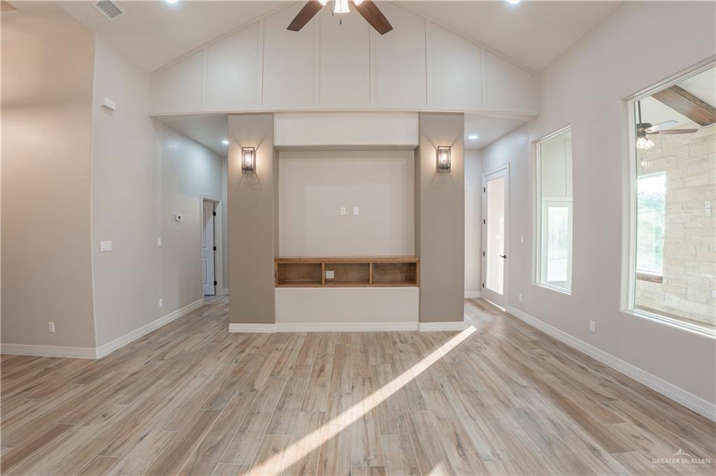 2618 Max Street Harlingen, TX 78552 - Photo 12 of 35 Spacious living area featuring vaulted ceilings, wood-finish flooring, and an integrated entertainment center with built-in shelving