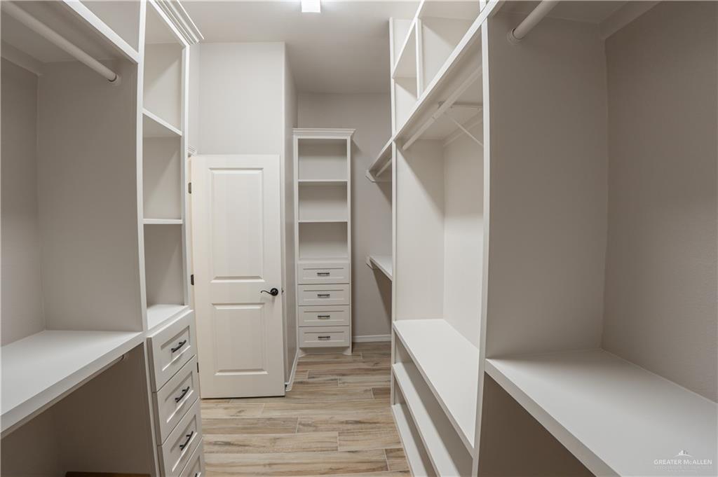 2618 Max Street Harlingen, TX 78552 - Photo 22 of 35 Walk-in closet featuring extensive built-in shelving, multiple hanging rods, integrated drawers with dark hardware, and wood-finish flooring