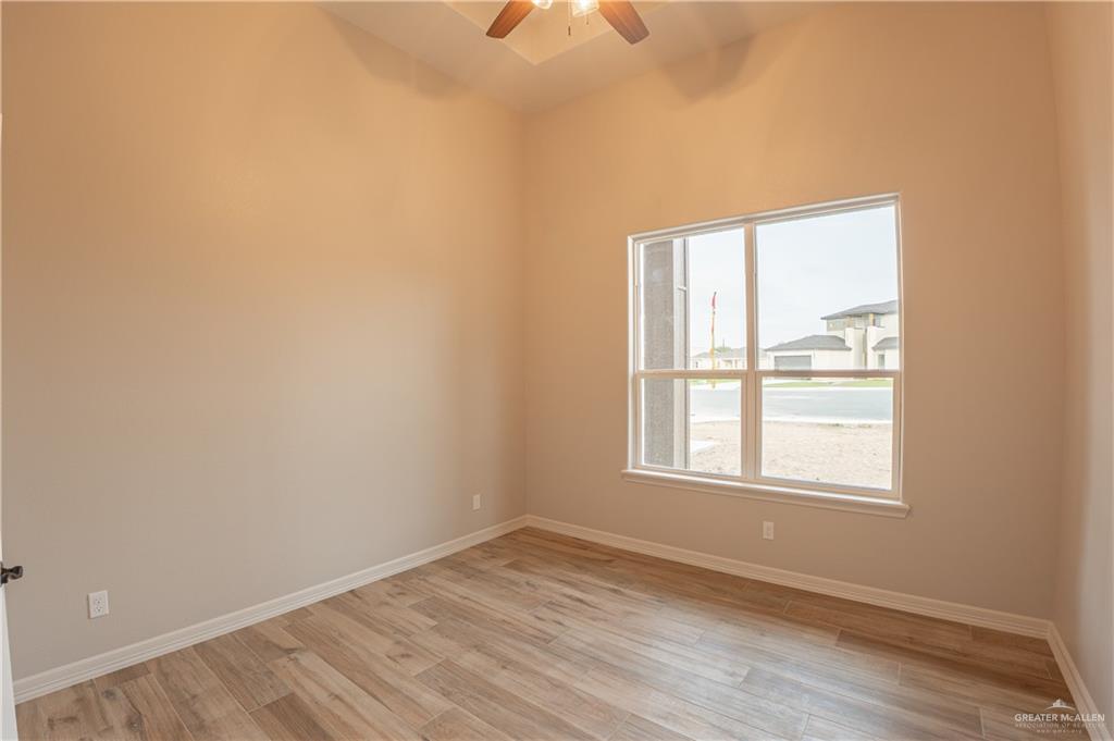 2618 Max Street Harlingen, TX 78552 - Photo 23 of 35 Neutral-toned interior room featuring wood-finish flooring, a ceiling fan with integrated lighting, and a large window providing natural illumination