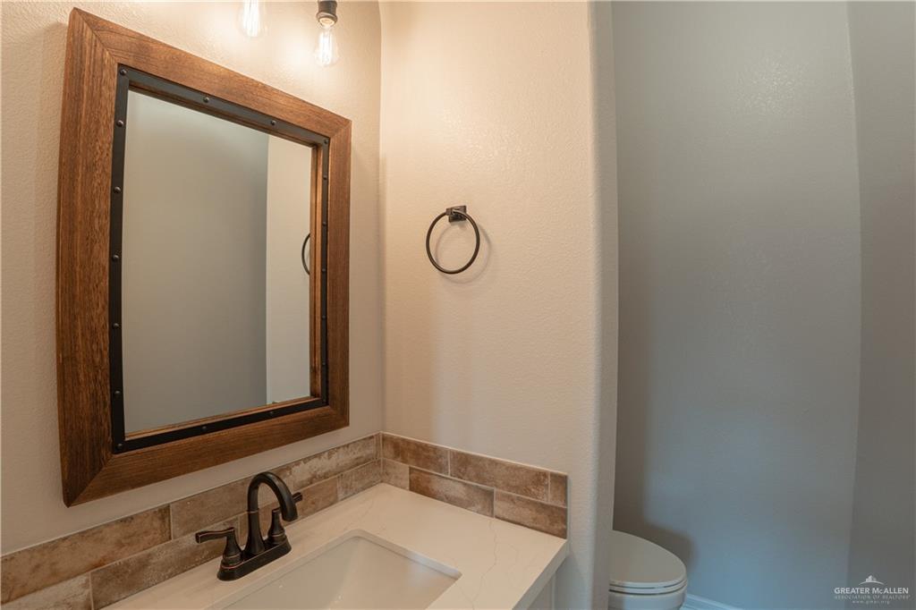 2618 Max Street Harlingen, TX 78552 - Photo 24 of 35 Bathroom vanity featuring a framed mirror with dark metal accents, a white countertop, and a bronze-finish faucet