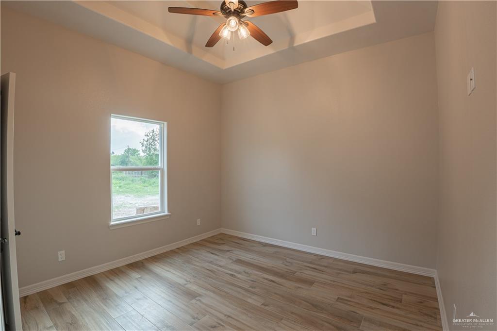 2618 Max Street Harlingen, TX 78552 - Photo 27 of 35 Interior room featuring wood-finish flooring, a single window, tray ceiling, and a ceiling fan with integrated lighting