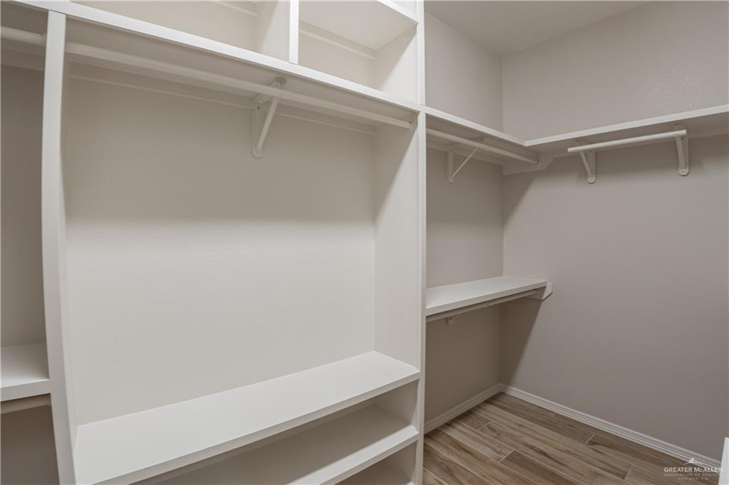 2618 Max Street Harlingen, TX 78552 - Photo 28 of 35 Custom white shelving system with integrated hanging rods, open storage compartments, and wood-finish flooring