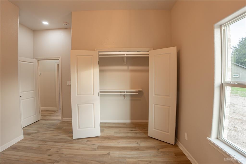 2618 Max Street Harlingen, TX 78552 - Photo 30 of 35 Recessed lighting illuminates this room featuring wood-finish flooring, a built-in closet with shelving and hanging rods, and a large window with white trim