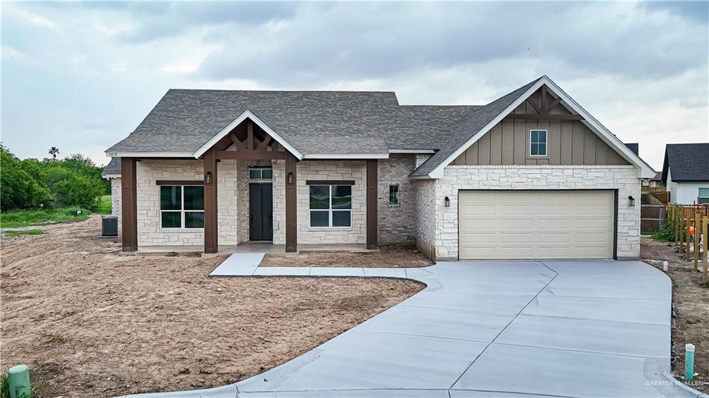 2618 Max Street Harlingen, TX 78552 - Photo 3 of 35 Stone veneer exterior with wood-look beam accents, dark shingle roofing, an attached two-car garage, and a concrete driveway