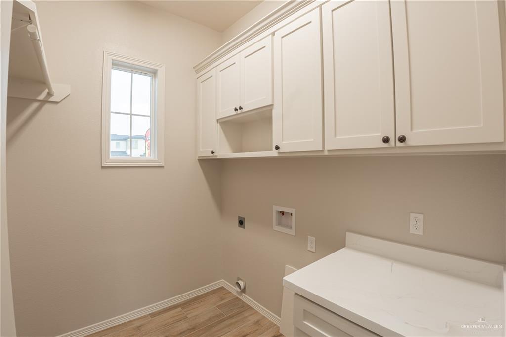 2618 Max Street Harlingen, TX 78552 - Photo 31 of 35 Utility room featuring shaker-style cabinetry, a built-in countertop, wood-finish tile flooring, and a window for natural light