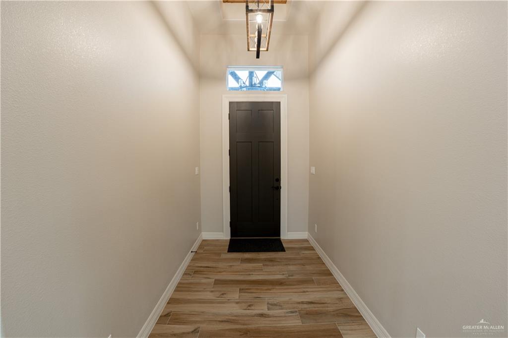 2618 Max Street Harlingen, TX 78552 - Photo 6 of 35 Entryway featuring wood-finish flooring, light neutral wall tones, a dark panel door, transom window, and a contemporary ceiling fixture
