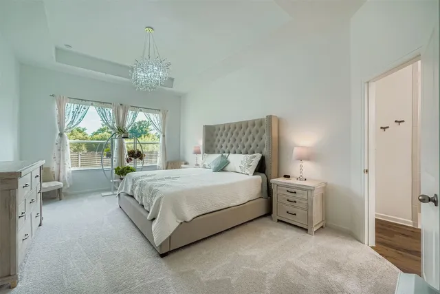 a spacious bedroom with a bed and a chandelier