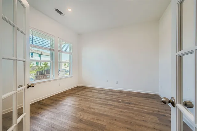 an empty room with wooden floor and windows