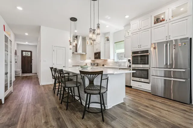 a kitchen with stainless steel appliances a dining table chairs stove and refrigerator