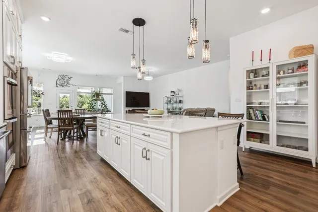 a kitchen with stainless steel appliances granite countertop a stove and chairs with wooden floor