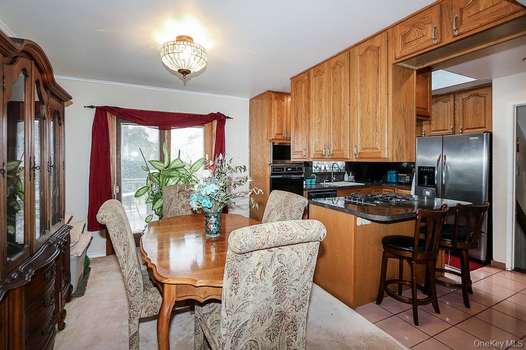 64 Conlon Road Roosevelt, NY 11575 - Photo 7 of 19 a kitchen with stainless steel appliances granite countertop a stove a refrigerator a dining table and chairs