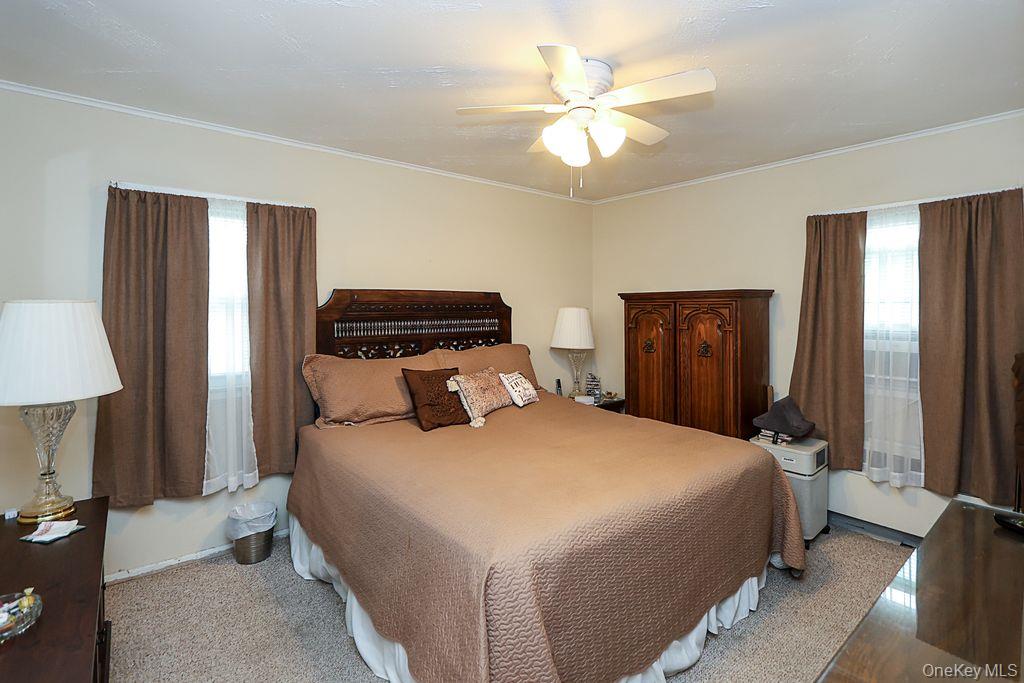 64 Conlon Road Roosevelt, NY 11575 - Photo 10 of 19 a bedroom with a large bed and a chandelier