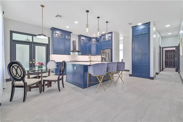 a room with stainless steel appliances kitchen island granite countertop furniture and a chandelier