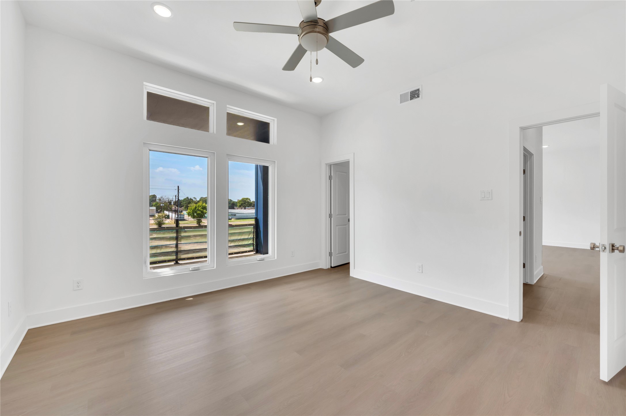 119 Kirby Road, Unit 5205 Seabrook, TX 77586 - Photo 27 of 46 Spacious bedroom featuring large windows that flood the room with natural light, complemented by sleek wood flooring and a modern ceiling fan.