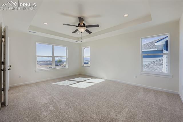 7989 Polson Drive Colorado Springs, CO 80908 - Photo 11 of 28 Unfurnished room featuring a tray ceiling, light carpet, a ceiling fan, and recessed lighting