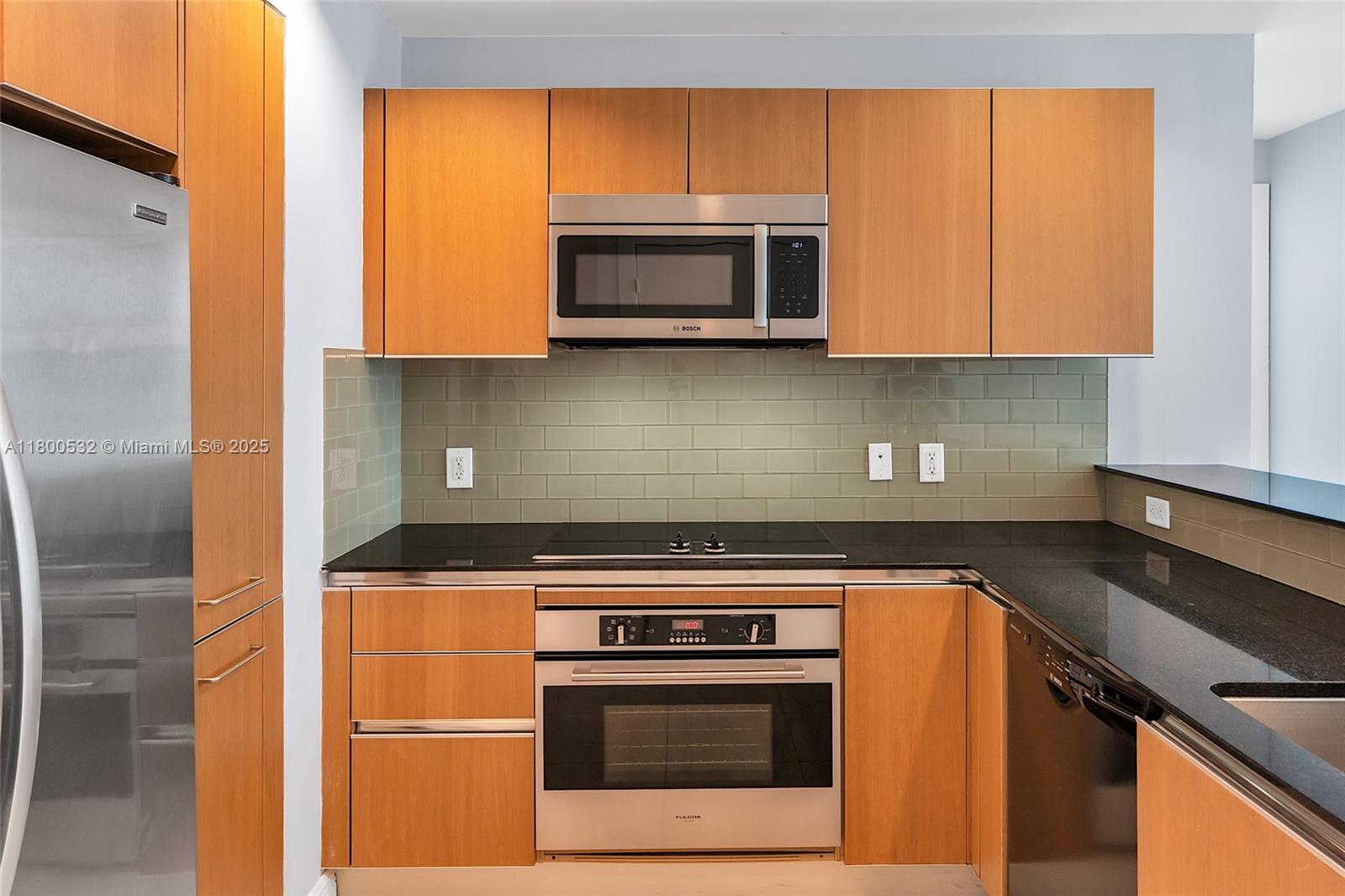 1060 Brickell Avenue, Unit 1811 Miami, FL 33131 - Photo 9 of 43 a kitchen with stainless steel appliances granite countertop a stove a microwave and a refrigerator