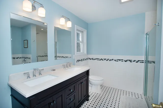 a bathroom with a sink a toilet a mirror and shower