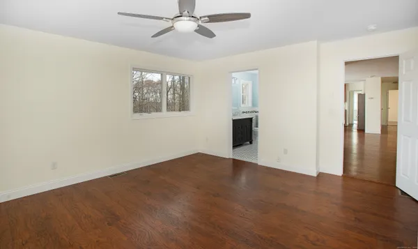 an empty room with wooden floor closet and windows