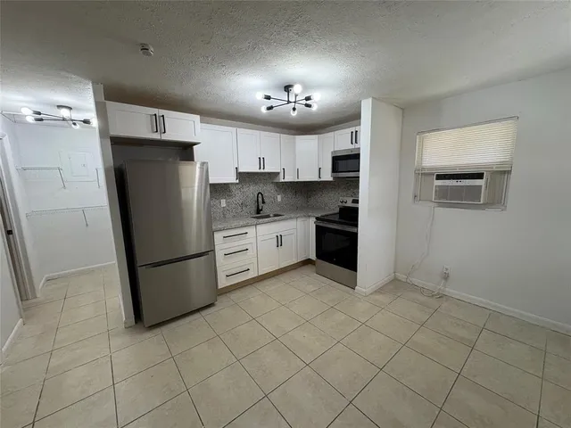 a kitchen with a refrigerator a stove top oven and cabinets