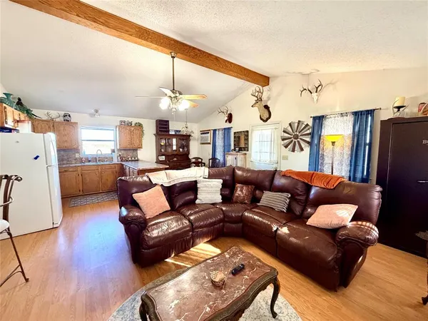 a living room with furniture kitchen view and a wooden floor