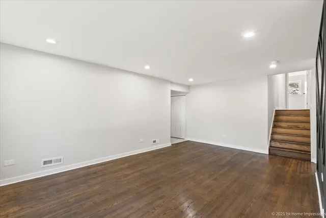an empty room with wooden floor and stairs