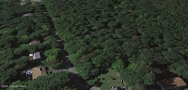 an aerial view of residential house with outdoor space and trees all around