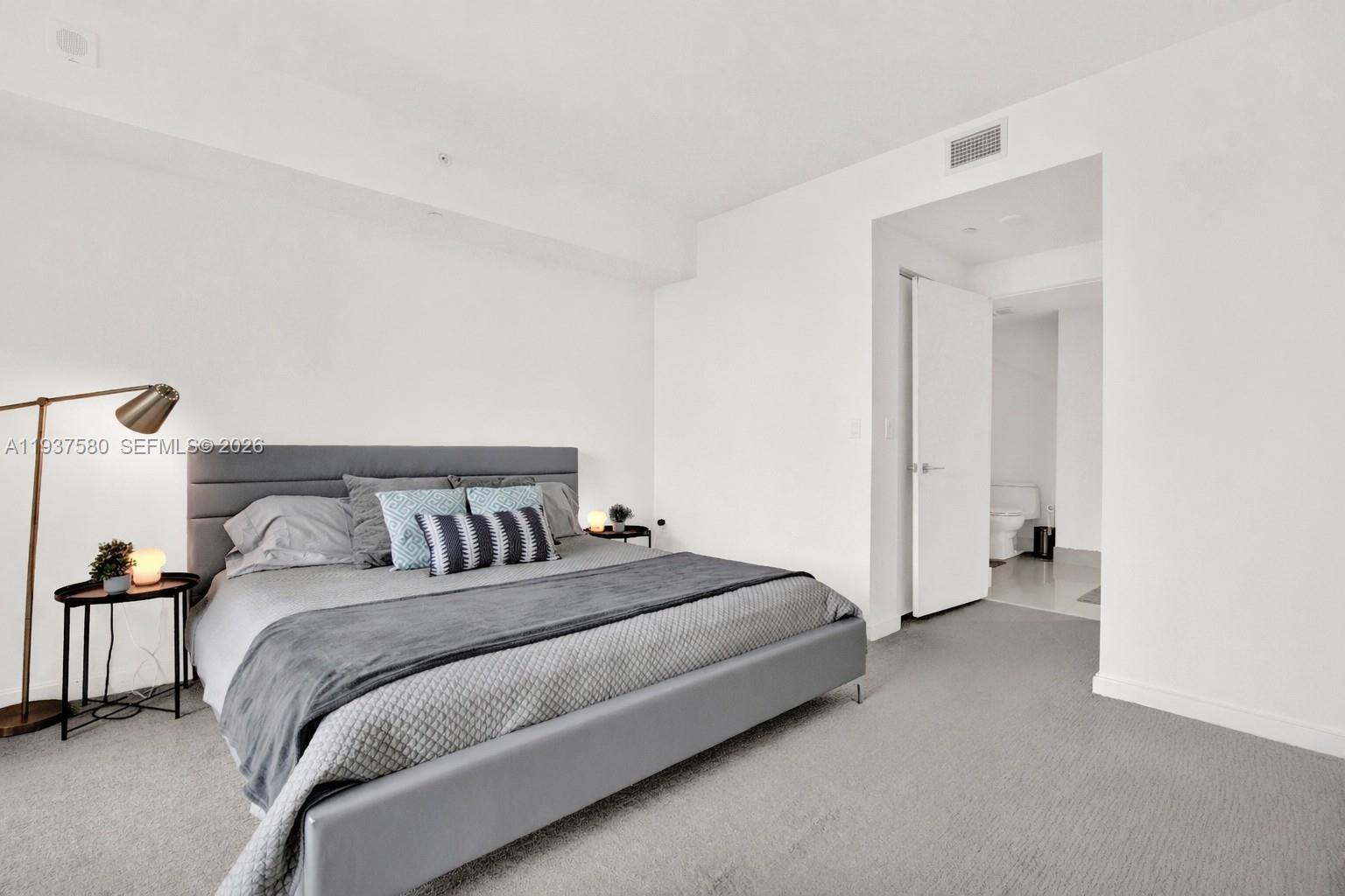 45 Southwest 9th Street, Unit 1609 Miami, FL 33130 - Photo 14 of 39 a spacious bedroom with a bed and a lamp