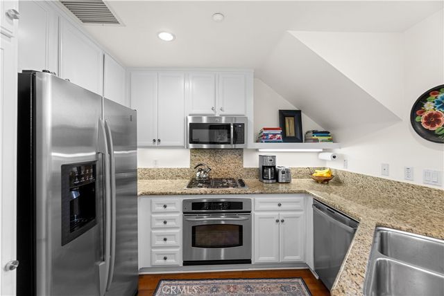 a kitchen with stainless steel appliances granite countertop a stove a refrigerator and a sink