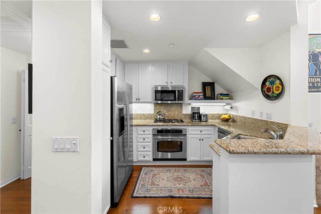 122 Jadestone Irvine, CA 92603 - Photo 10 of 20 a kitchen with granite countertop stainless steel appliances a stove top oven a sink and cabinets