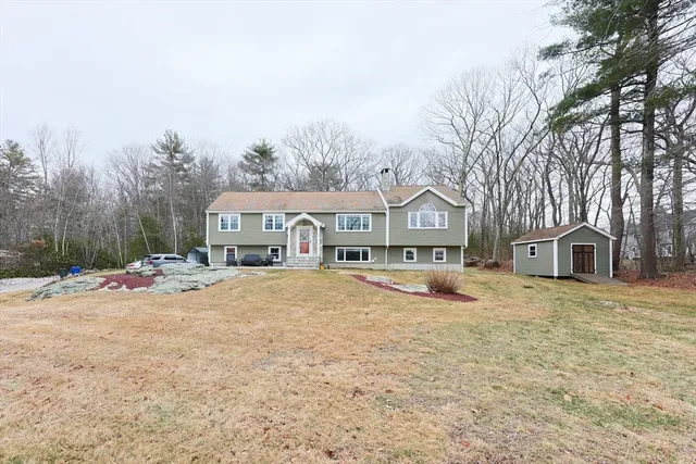 a front view of a house with a yard and large trees