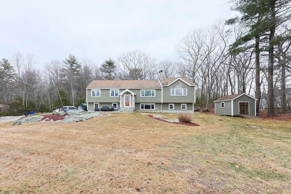 a front view of a house with a yard and large trees