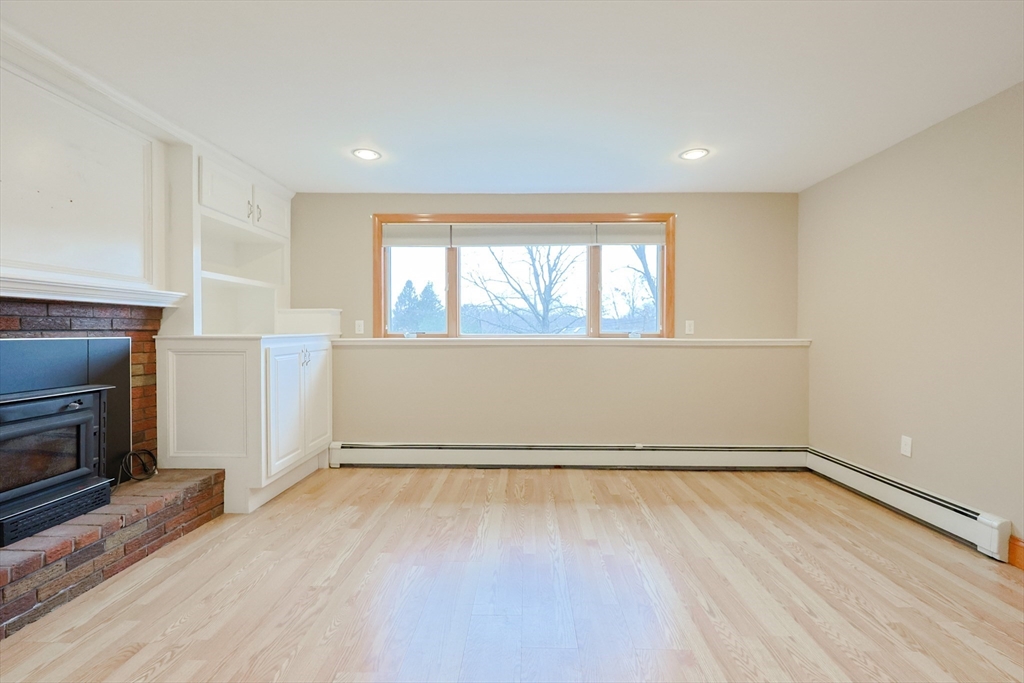 68 Greene Street, Unit A Hopedale, MA 01747 - Photo 13 of 26 an empty room with wooden floor fireplace and windows