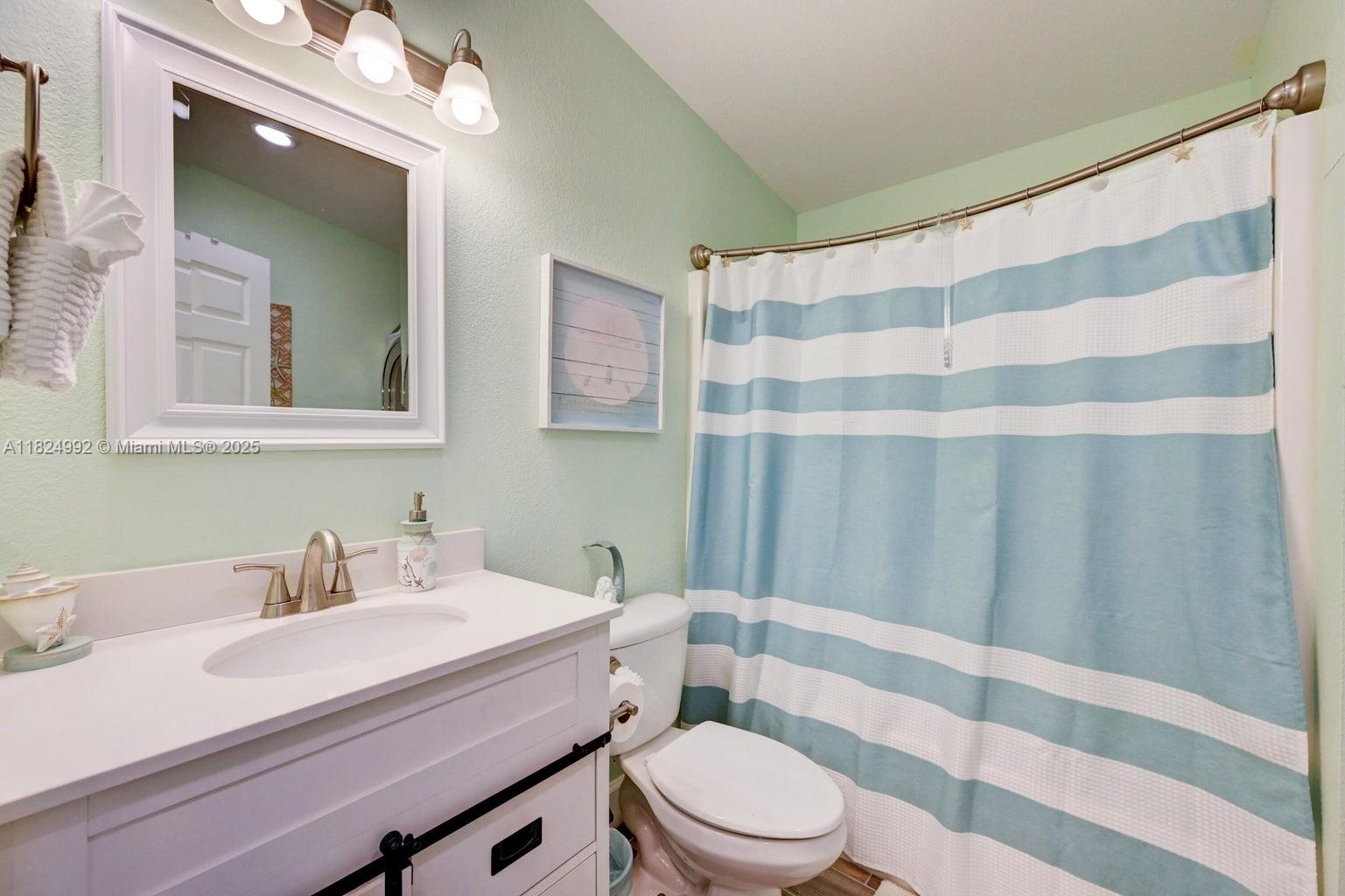 239 Lower Matecumbe Road Key Largo, FL 33037 - Photo 28 of 70 a bathroom with a sink a toilet a mirror and shower curtain