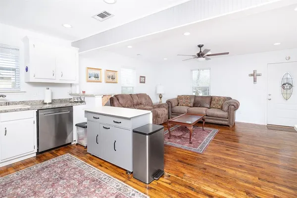 a living room with stainless steel appliances kitchen island granite countertop a sink and a stove top oven