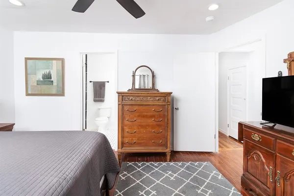 a bedroom with a bed and a flat tv screen on a dresser