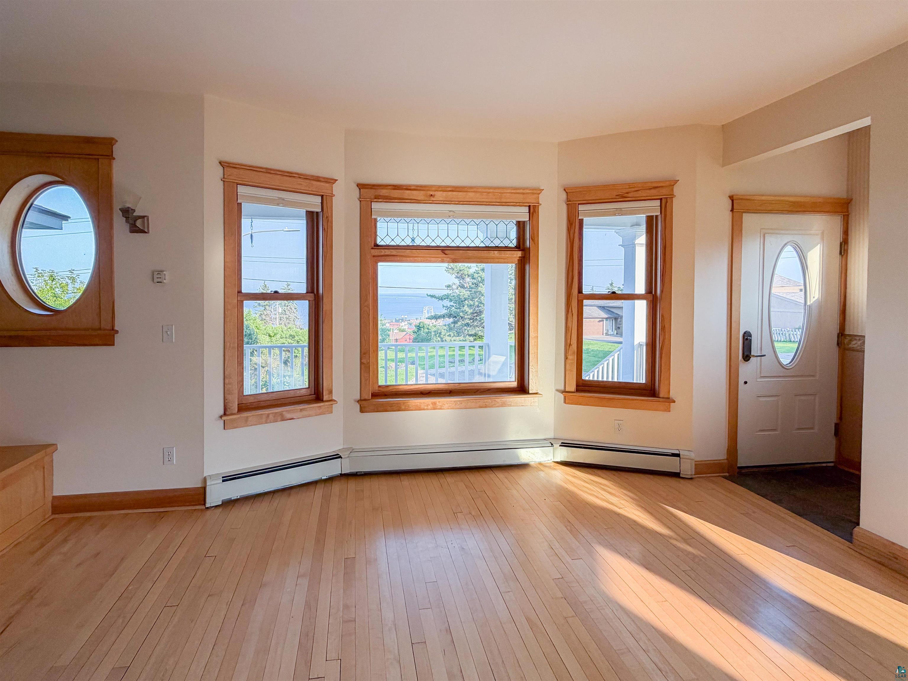 13 West 8th Street Duluth, MN 55806 - Photo 4 of 57 Living space with light wood-finish flooring, bay windows with wood trim, and a decorative circular window