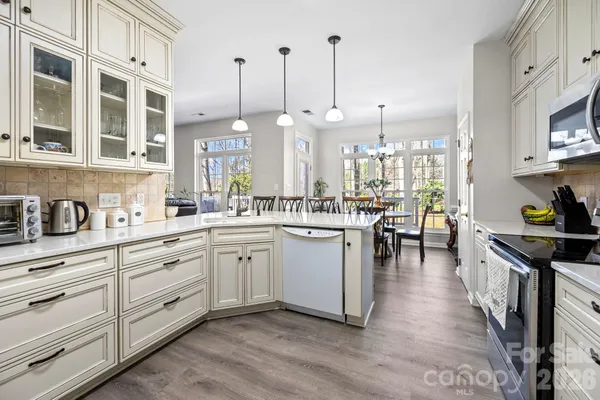 a kitchen with stainless steel appliances kitchen island granite countertop a stove a sink and white cabinets