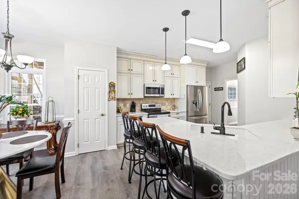 a kitchen with stainless steel appliances kitchen island granite countertop a table chairs and a refrigerator
