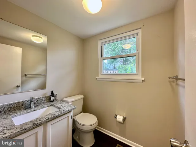 a bathroom with a granite countertop sink toilet and mirror