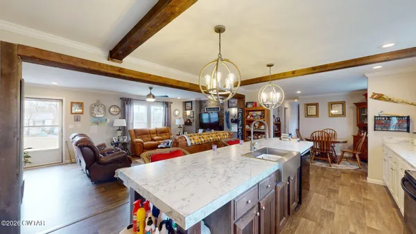 a view of a dining room and livingroom with furniture wooden floor a chandelier