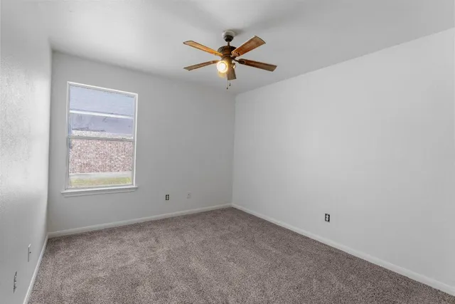 an empty room with a window and a ceiling fan