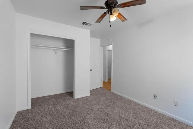 an empty room with closet and a chandelier fan