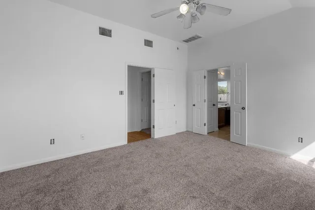 a view of an empty room with a chandelier fan
